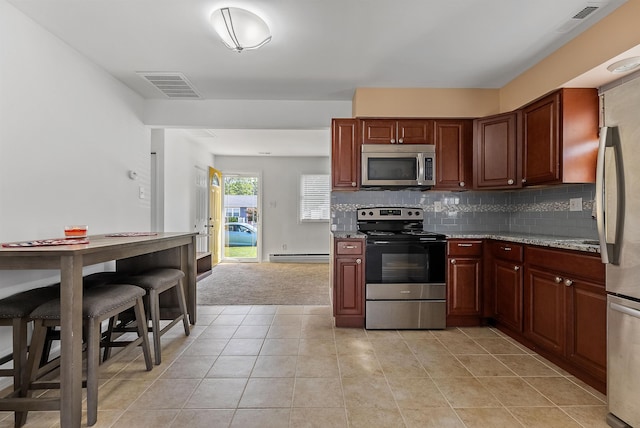 kitchen with light tile patterned floors, appliances with stainless steel finishes, visible vents, a baseboard heating unit, and backsplash