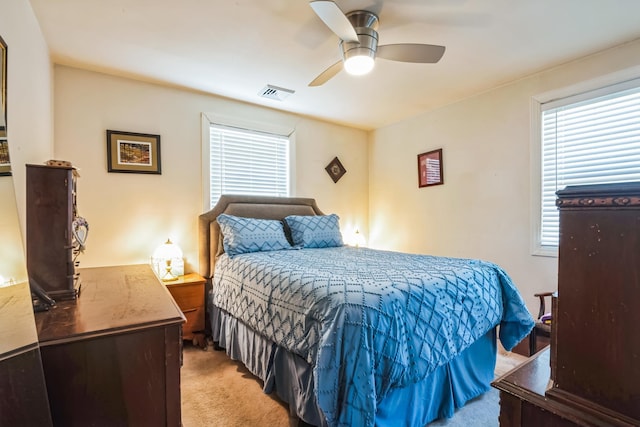 bedroom featuring a ceiling fan, visible vents, and light carpet