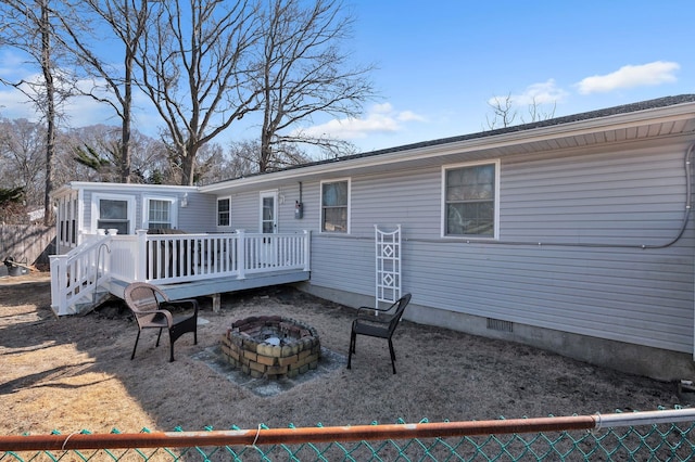 back of house with a deck, an outdoor fire pit, crawl space, and fence