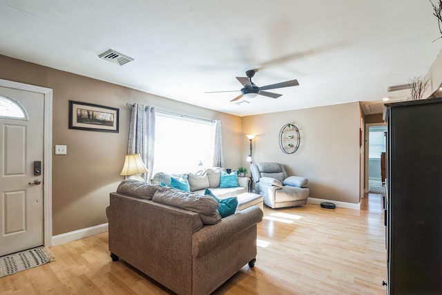 living area featuring baseboards, a ceiling fan, visible vents, and light wood-style floors