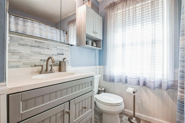 full bathroom featuring a wainscoted wall, plenty of natural light, vanity, and toilet