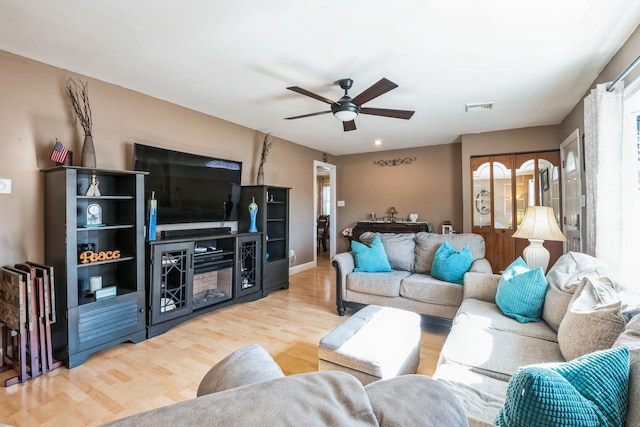 living room featuring a ceiling fan, baseboards, visible vents, and wood finished floors