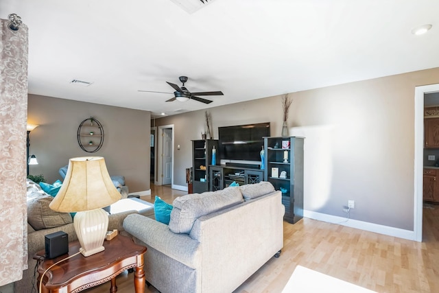 living room with visible vents, wood finished floors, a ceiling fan, and baseboards