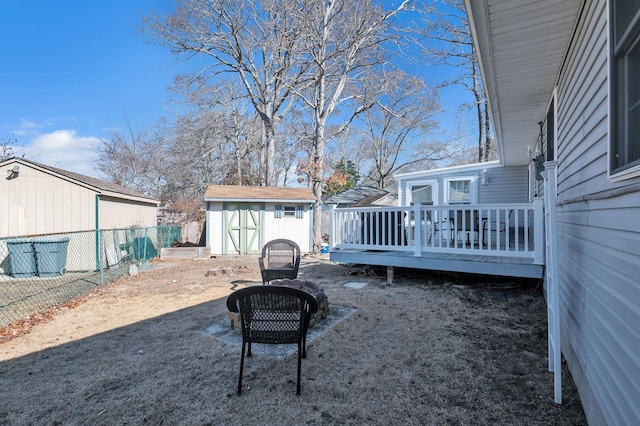 view of yard featuring a deck, a storage shed, an outbuilding, and fence