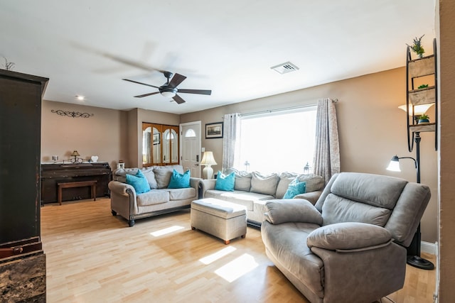 living room with light wood-style flooring, visible vents, and ceiling fan