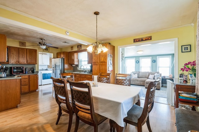 dining area with ceiling fan with notable chandelier, ornamental molding, a wealth of natural light, and light wood-style floors