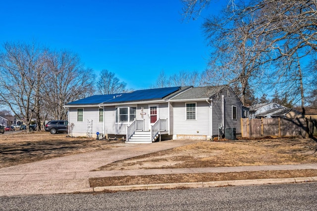 view of front of home featuring central AC, fence, dirt driveway, and solar panels