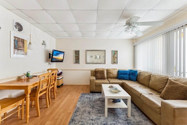 living room with a paneled ceiling, ceiling fan, and light hardwood / wood-style flooring