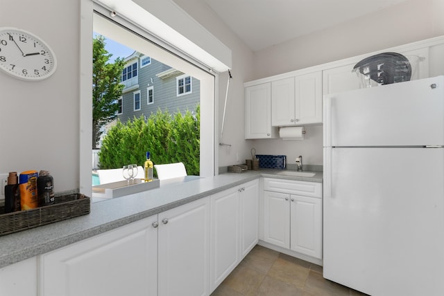 kitchen featuring white fridge, white cabinetry, and sink