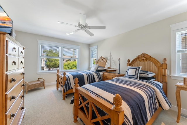 carpeted bedroom featuring multiple windows and ceiling fan