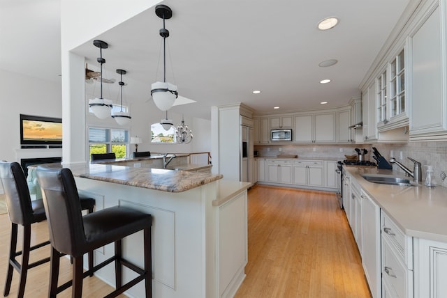 kitchen with tasteful backsplash, built in appliances, decorative light fixtures, a breakfast bar area, and white cabinets