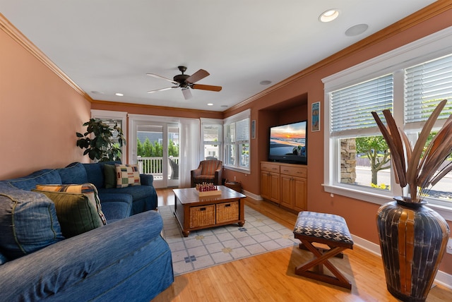 living room featuring light wood-type flooring, a wealth of natural light, ornamental molding, and ceiling fan