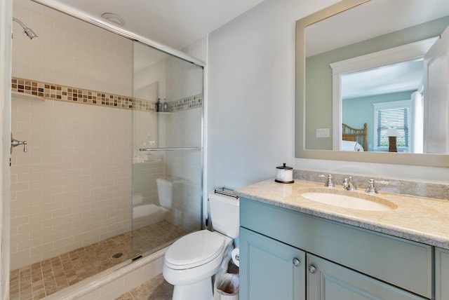 bathroom with a shower with door, vanity, and toilet