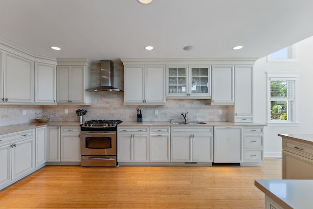 kitchen featuring stainless steel range with gas cooktop, light hardwood / wood-style floors, wall chimney range hood, and sink