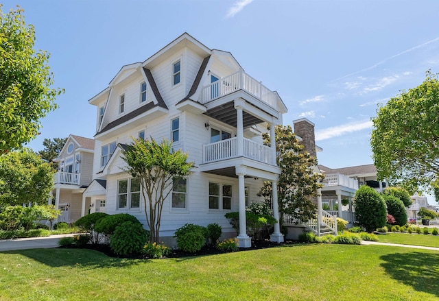 view of front of property with a balcony and a front lawn