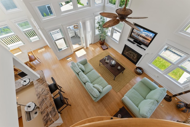 living room with a high ceiling, ceiling fan, and wood-type flooring