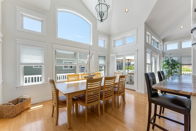 dining space featuring light hardwood / wood-style flooring, high vaulted ceiling, and a chandelier