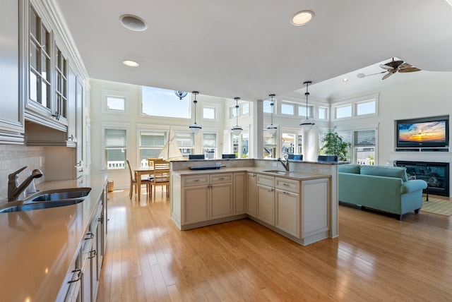 kitchen featuring sink, decorative light fixtures, ceiling fan, and an island with sink