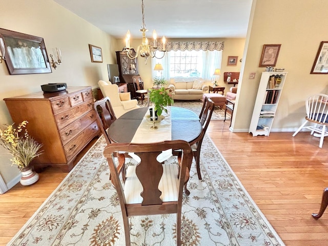 dining space with baseboards, a notable chandelier, and light wood-style flooring