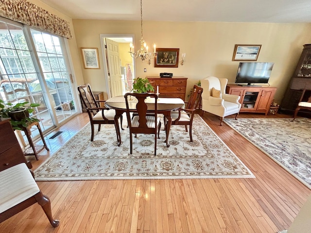 dining area with wood-type flooring and a chandelier