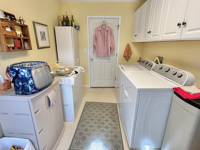 washroom with cabinet space, baseboards, light floors, and washer and clothes dryer