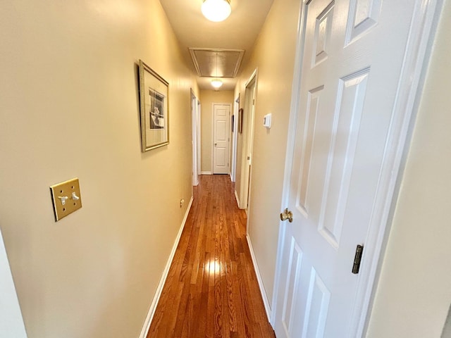 corridor with attic access, wood finished floors, and baseboards