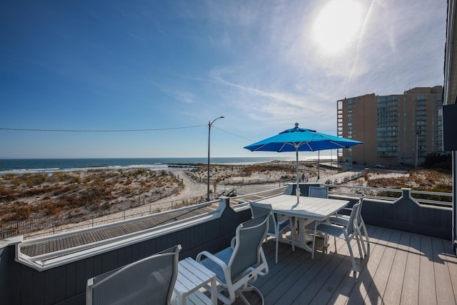 wooden terrace featuring a water view and a view of the beach