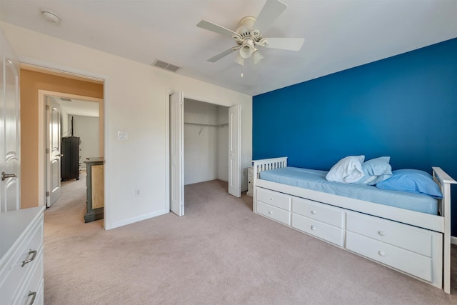 bedroom with ceiling fan, light colored carpet, visible vents, baseboards, and a closet