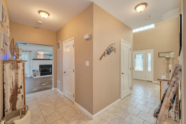 foyer featuring light tile patterned flooring, a fireplace, and baseboards