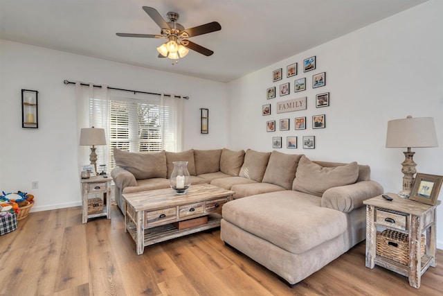 living area featuring a ceiling fan, light wood-style flooring, and baseboards