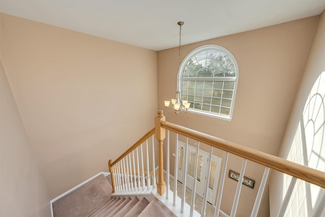 stairway with baseboards, a chandelier, and carpet flooring