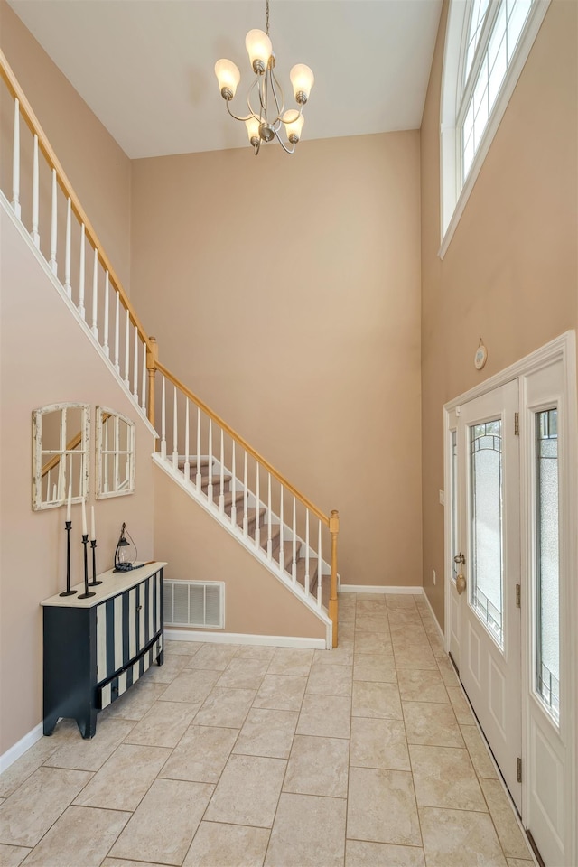 tiled entryway with visible vents, a notable chandelier, stairway, and baseboards