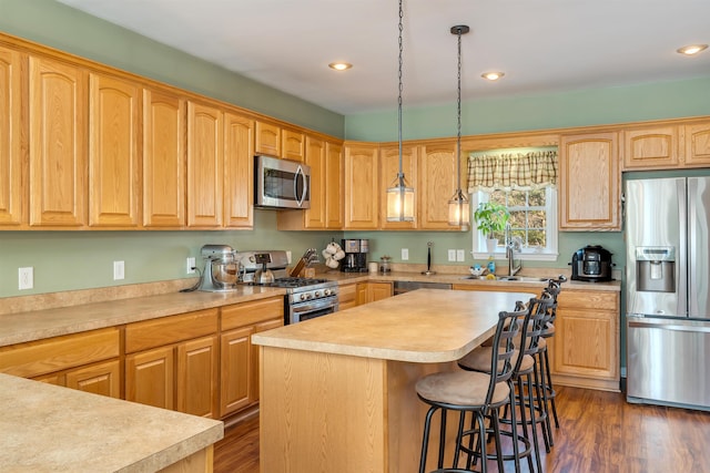 kitchen featuring appliances with stainless steel finishes, a kitchen breakfast bar, dark wood-type flooring, light countertops, and a sink