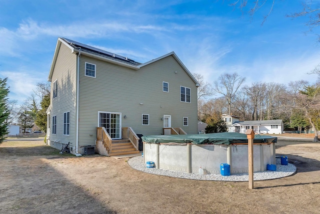 rear view of house featuring solar panels, central AC, and a covered pool