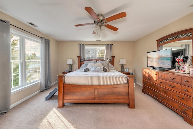 bedroom with a ceiling fan, light colored carpet, visible vents, and baseboards