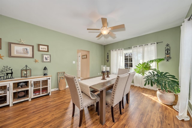 dining area with a ceiling fan, baseboards, and wood finished floors