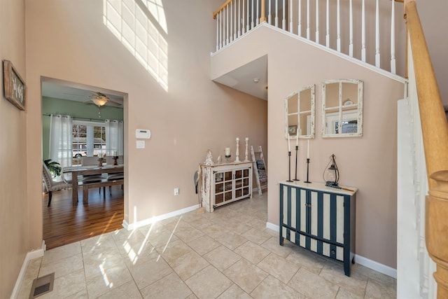 interior space with a towering ceiling, ceiling fan, and baseboards