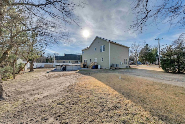 rear view of house with central AC, fence, and an outdoor pool