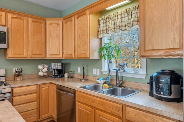 kitchen with light brown cabinets, appliances with stainless steel finishes, light countertops, and a sink