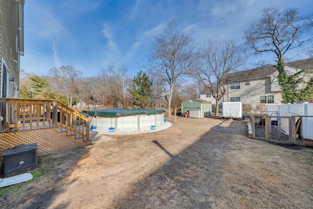 view of yard with a covered pool, an outbuilding, a storage unit, fence, and cooling unit