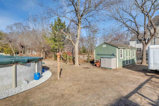 view of yard featuring a garage, a covered pool, an outdoor structure, and a storage unit