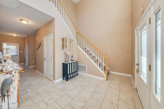 entrance foyer featuring stairs, a wealth of natural light, visible vents, and baseboards