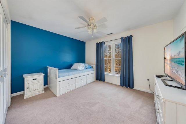 bedroom featuring a ceiling fan, visible vents, light carpet, and baseboards