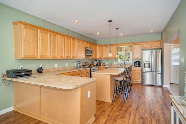 kitchen with stainless steel appliances, light brown cabinets, light countertops, and a healthy amount of sunlight