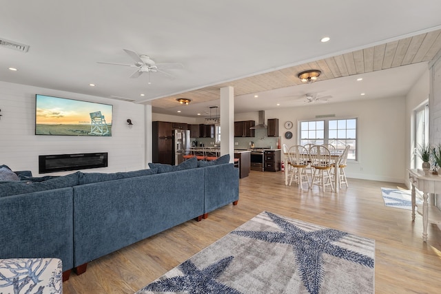 living room with recessed lighting, a ceiling fan, visible vents, light wood-style floors, and a glass covered fireplace