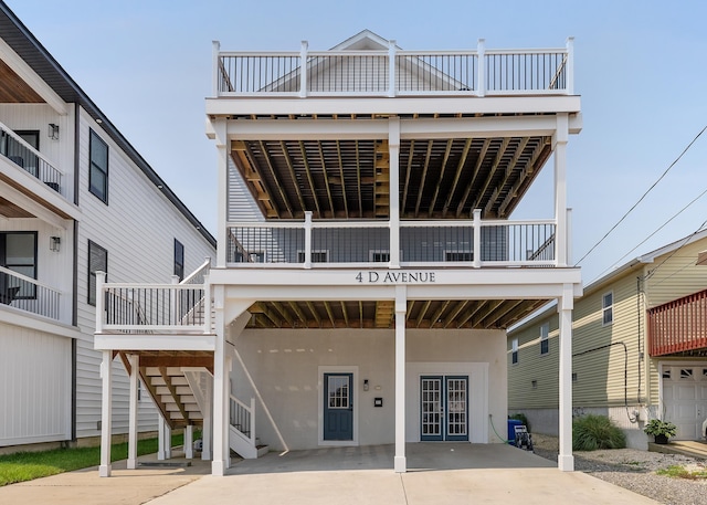 rear view of property with stairs, concrete driveway, and stucco siding