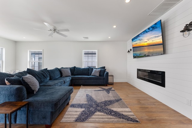 living area featuring a wealth of natural light, a large fireplace, visible vents, and wood finished floors