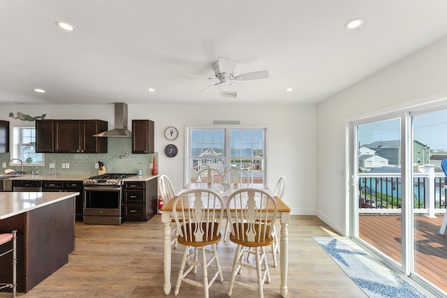 interior space with tasteful backsplash, wall chimney exhaust hood, stainless steel appliances, dark brown cabinets, and light countertops