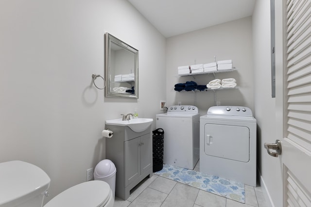 half bathroom featuring vanity, tile patterned floors, toilet, and washer and dryer