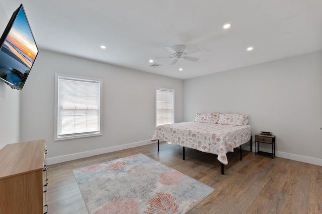 bedroom featuring light wood finished floors, baseboards, multiple windows, and visible vents